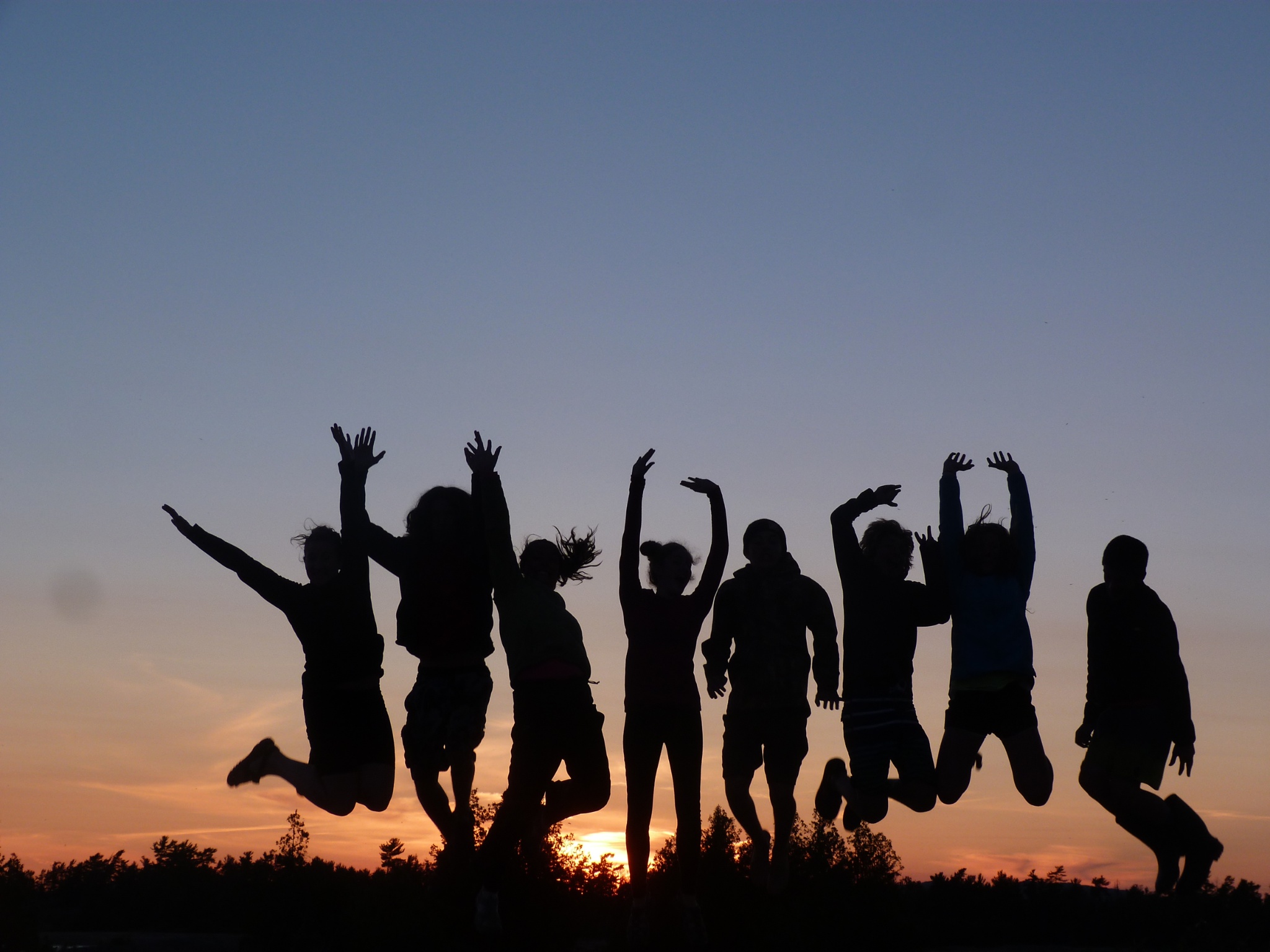 A group of students jumping in the air at sunset